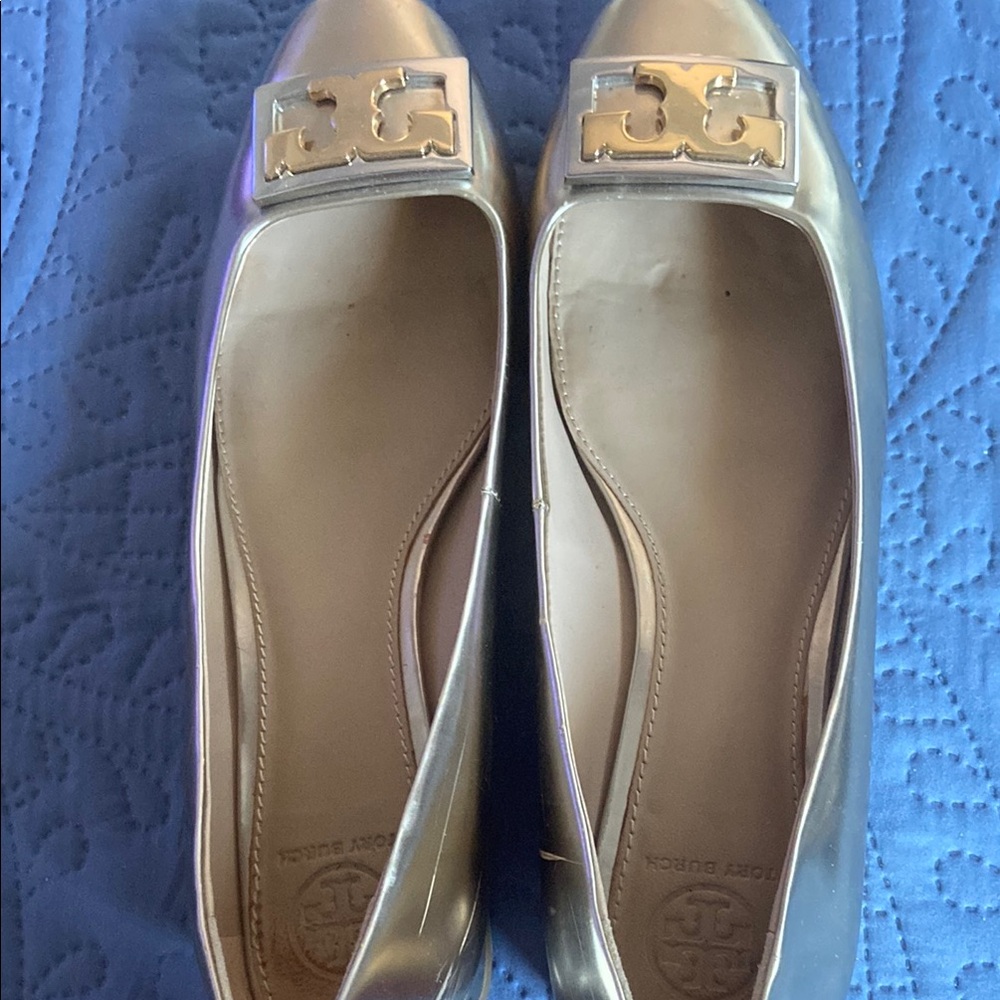 Tory Burch golden shoe with gold Tory Burch logo on toes.